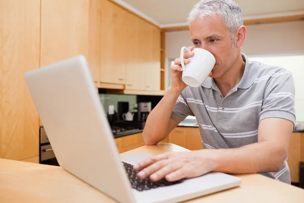 Homme heureux utilisant un ordinateur portable tout en buvant du café — Photo