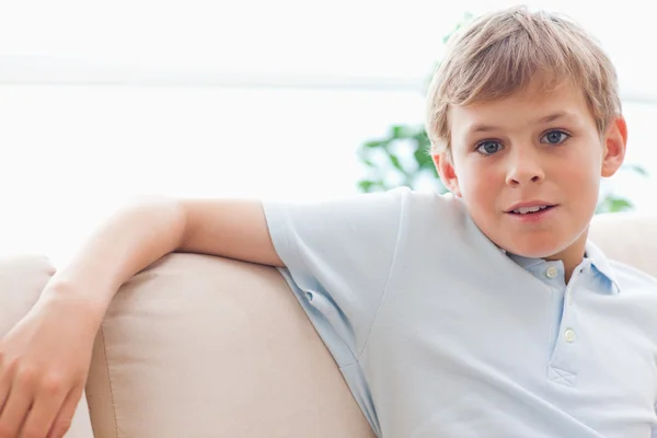 Pojken lutar sig på en soffa — Stockfoto