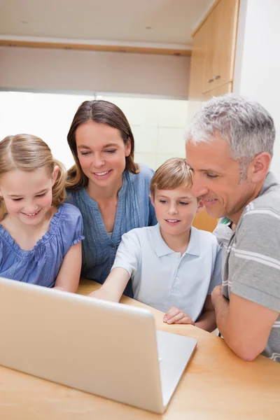 Porträtt av en härlig familj som använder en bärbar dator — Stockfoto