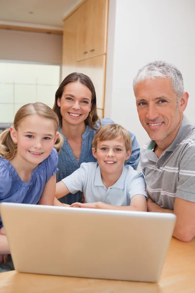 Retrato de uma família encantadora usando um laptop — Fotografia de Stock