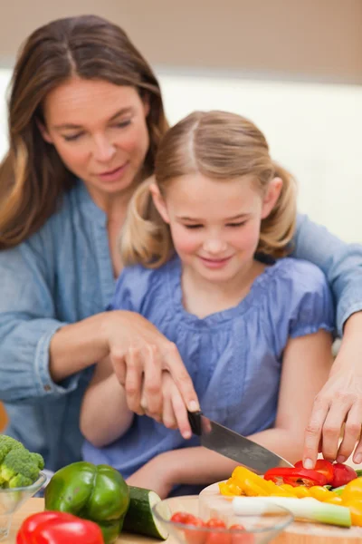 Portrait of a mother slicing pepper with her daughter — Stock Photo, Image