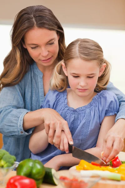 Portrait of a woman slicing pepper with her daughter — Stock Photo, Image