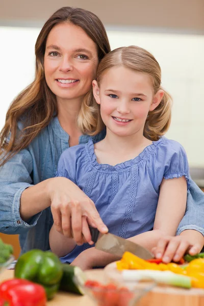 Portrait of a woman slicing bell pepper with her daughter — Stock Photo, Image