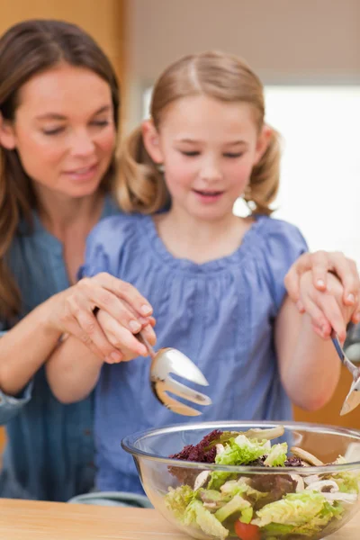 Retrato de uma mulher preparando uma salada com sua filha — Fotografia de Stock