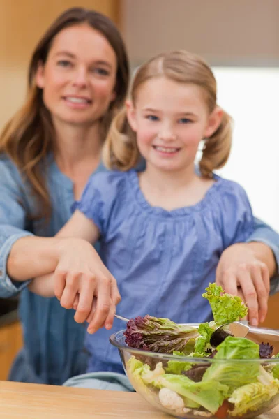 Retrato de uma mulher feliz preparando uma salada com sua filha — Fotografia de Stock