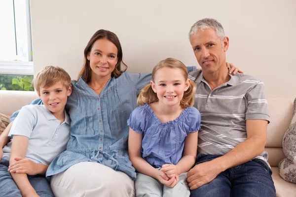 Famiglia felice seduta su un divano — Foto Stock