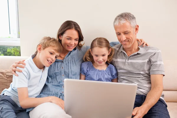 Famille assise sur un canapé à l'aide d'un ordinateur portable — Photo