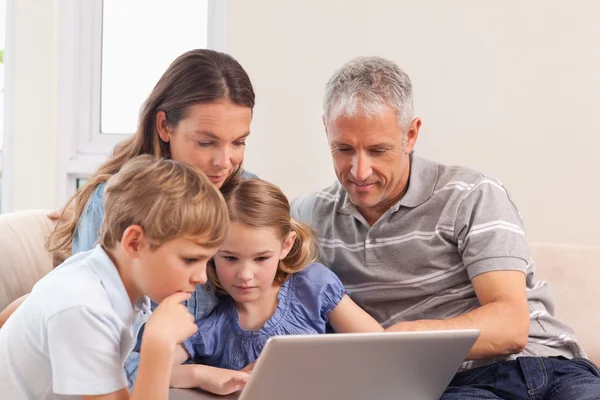 Zittend op een bank met behulp van een laptop en gelukkige familie — Stockfoto