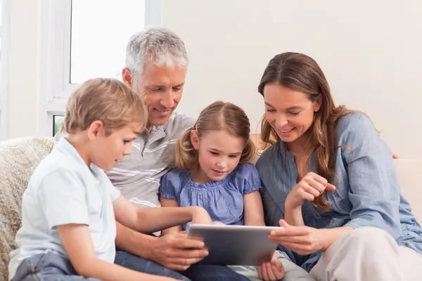 Família feliz usando um computador tablet — Fotografia de Stock