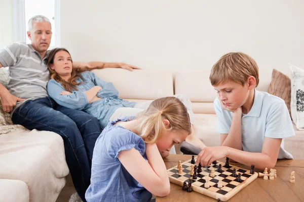 Дети играют в шахматы перед родителями — стоковое фото