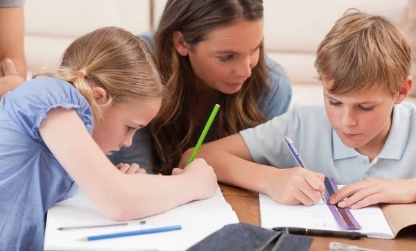 Mother helping her children to do their homework — Stock Photo, Image