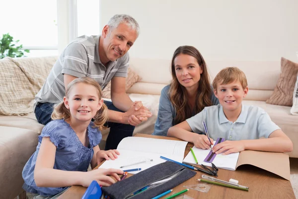 그들의 숙제를 할 그녀의 아이 들을 돕는 행복 한 부모 — 스톡 사진
