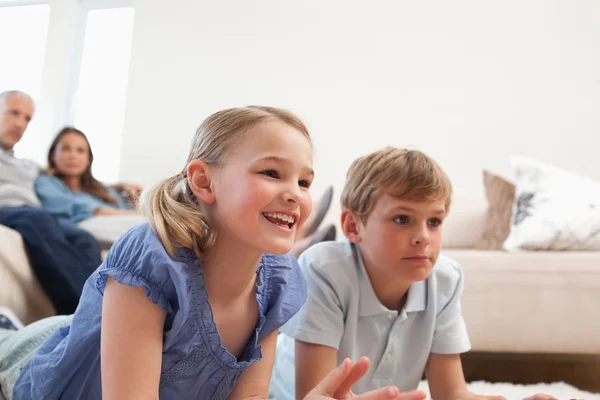 Crianças jogando videogames enquanto seus pais assistem — Fotografia de Stock