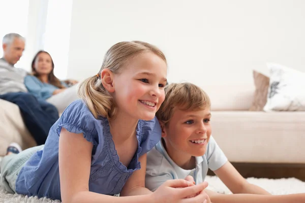 Siblings playing video games while their parents are watching — Stock Photo, Image