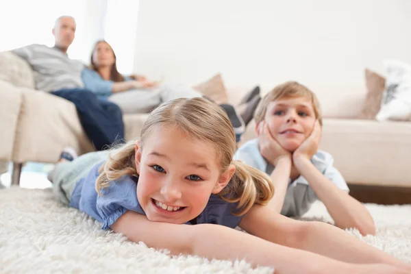 Siblings lying on a carpet — Stock Photo, Image