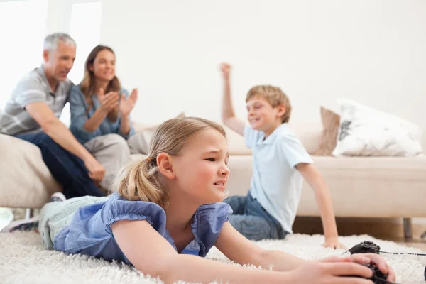 Bambini carini che giocano ai videogiochi con i loro genitori sul retro — Foto Stock