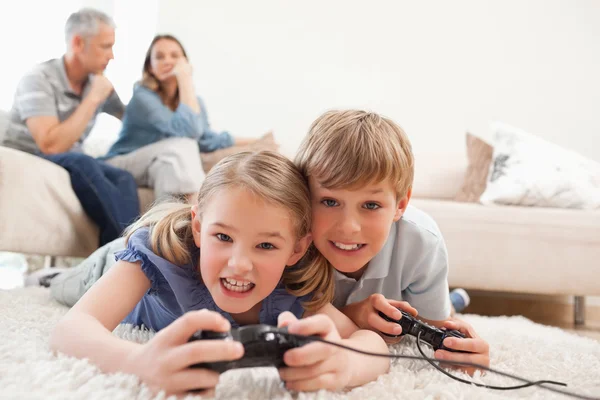 Χαρούμενα παιδιά που παίζουν βιντεοπαιχνίδια με τους γονείς τους σχετικά με την — Φωτογραφία Αρχείου
