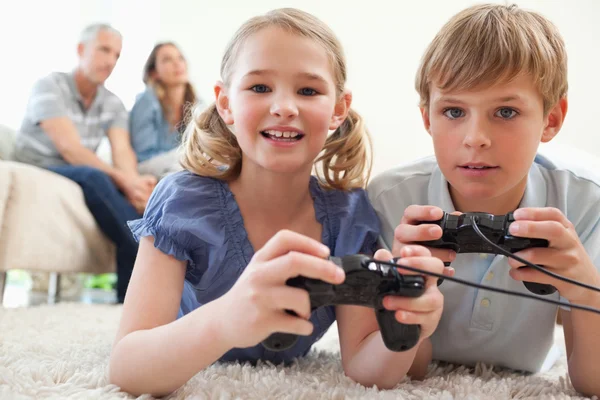 Juguetones hermanos jugando videojuegos con sus padres en el b — Foto de Stock