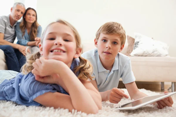 Счастливые дети, пользующиеся планшетным компьютером со своими родителями на — стоковое фото