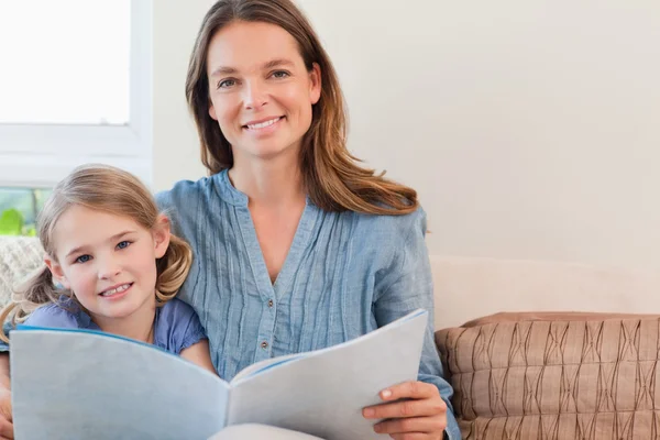 Glad mamma läser en bok till sin dotter — Stockfoto