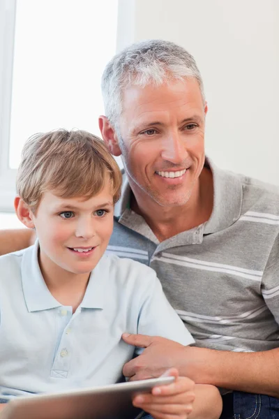 一个微笑着的父亲和他的儿子使用一款平板电脑的肖像 — 图库照片