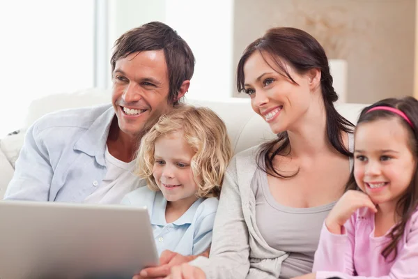 Glad familj använder en bärbar dator — Stockfoto