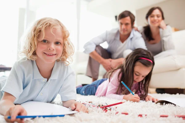 Crianças desenhando enquanto seus pais estão em segundo plano — Fotografia de Stock
