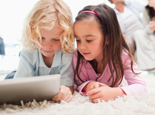 Дети, использующие планшетный компьютер, пока их родители находятся в — стоковое фото