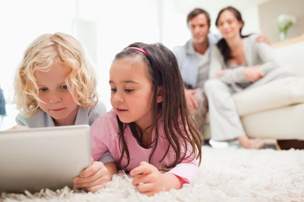 Милі брати і сестри використовують планшетний комп'ютер, поки їхні батьки знаходяться — стокове фото