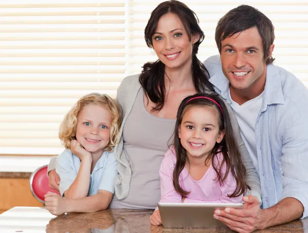 Família sorrindo usando um computador tablet juntos — Fotografia de Stock