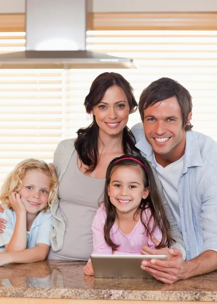 Retrato de uma família sorrindo usando um computador tablet juntos — Fotografia de Stock