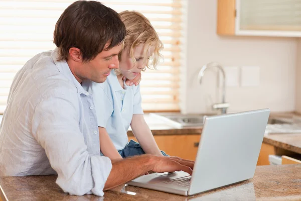 男孩和他父亲一起使用一台笔记本电脑 — 图库照片