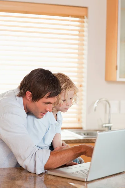 Portrait of a boy and his father using a laptop together — Stock Photo, Image
