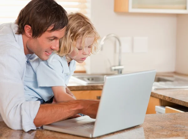 Rapaz bonito e seu pai usando um laptop juntos — Fotografia de Stock