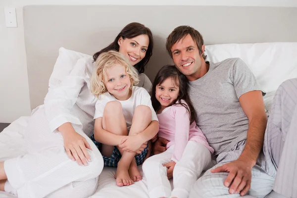 Sorrindo família posando em uma cama — Fotografia de Stock