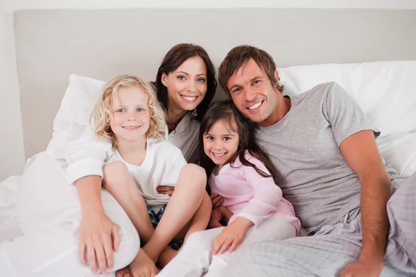 Família feliz posando em uma cama — Fotografia de Stock