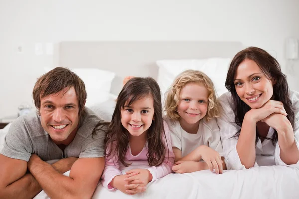 Liggend in een bed en gelukkige familie — Stockfoto