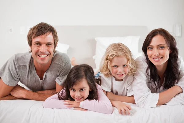 Lachende familie liggen in een bed — Stockfoto