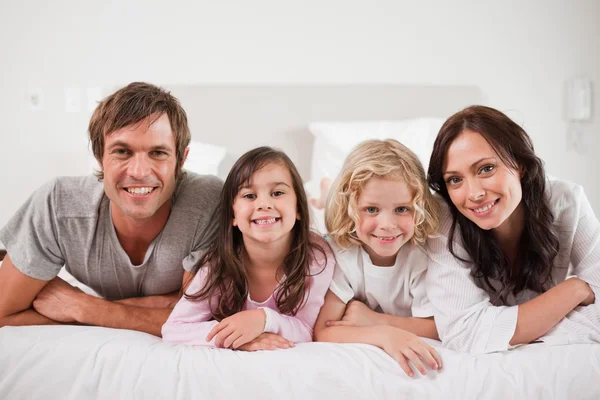 Glad familj ligger i en säng — Stockfoto