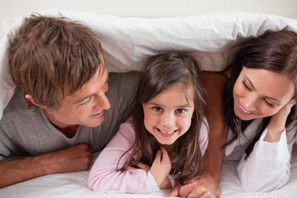 Fröhliche Familie liegt unter einer Bettdecke — Stockfoto