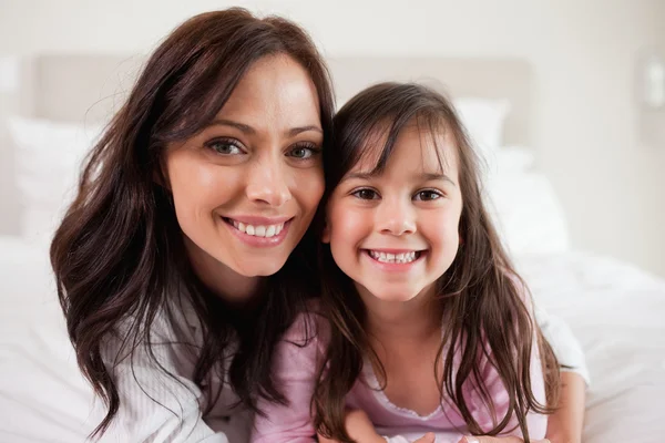 Girl and her mother lying on a bed — Stock Photo, Image