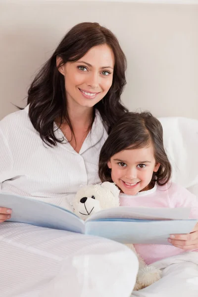 Portret van een gelukkige moeder lezen een verhaal aan haar dochter — Stockfoto
