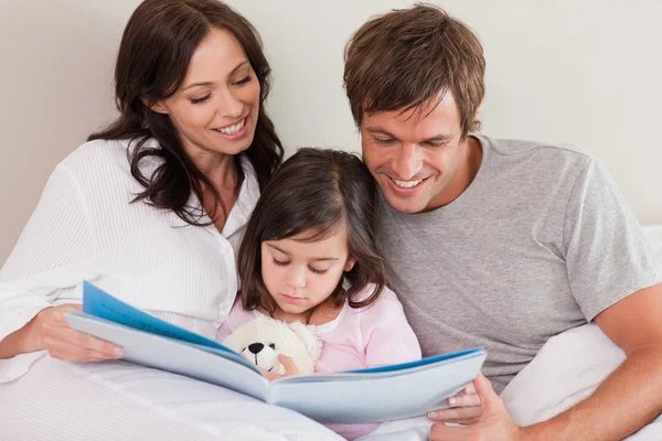 Lyckliga föräldrar läser en historia till sin dotter — Stockfoto