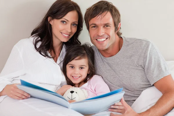 Lachende ouders lezen van een verhaal van hun dochter — Stockfoto