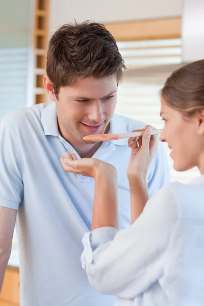 Retrato de um homem bonito provando o molho de sua esposa — Fotografia de Stock