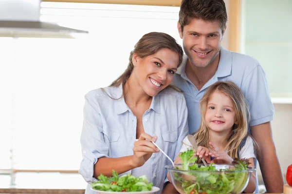 Lächelnde Familie bereitet einen Salat zu — Stockfoto