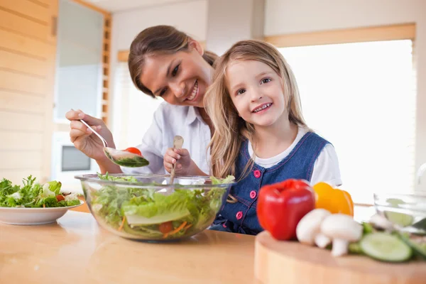 Mãe feliz e sua filha preparando uma salada — Fotografia de Stock