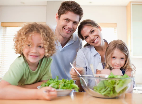 Famille souriante préparant une salade ensemble — Photo