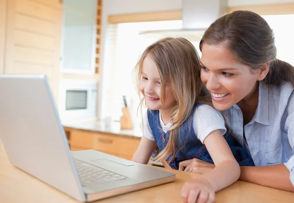 Anne ve kızı bir dizüstü bilgisayar kullanarak gülümseyen — Stok fotoğraf