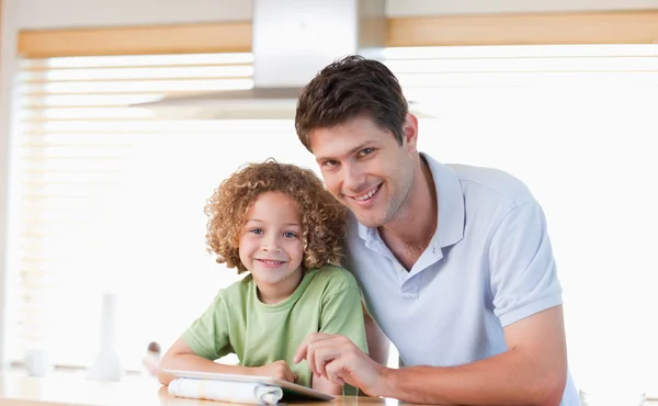 Sorridente ragazzo e suo padre utilizzando un computer tablet — Foto Stock